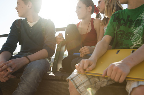 A group of teens sitting on a bench.